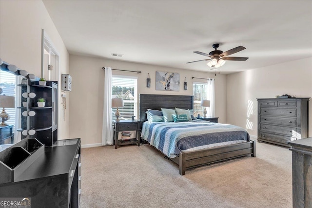 bedroom with light carpet, ceiling fan, multiple windows, and baseboards