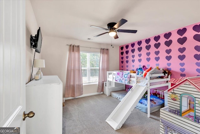 carpeted bedroom with wallpapered walls, visible vents, baseboards, ceiling fan, and an accent wall