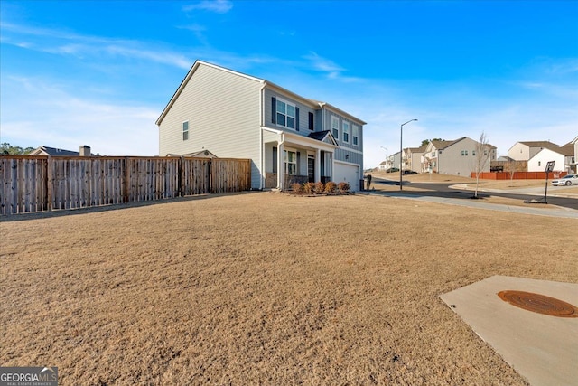 exterior space with a garage, a yard, fence, and a residential view