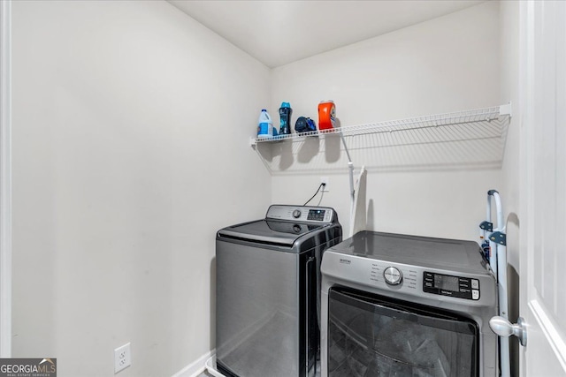 washroom featuring washing machine and dryer, laundry area, and baseboards