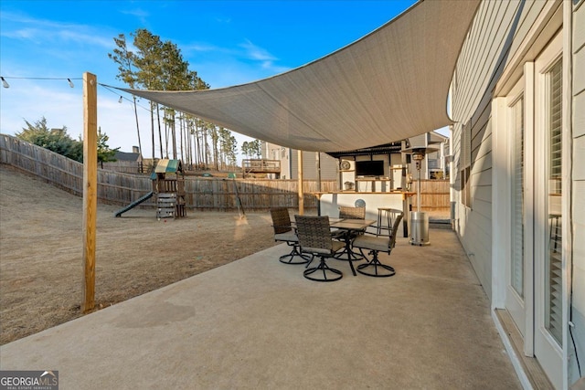 view of patio / terrace with outdoor dining area, a fenced backyard, and a playground