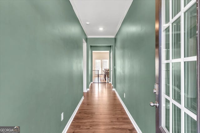 hallway with crown molding, baseboards, and wood finished floors