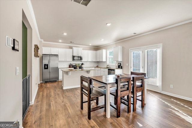 dining room with recessed lighting, visible vents, baseboards, wood-type flooring, and crown molding