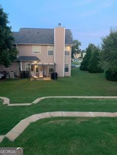 exterior space featuring a chimney and a lawn