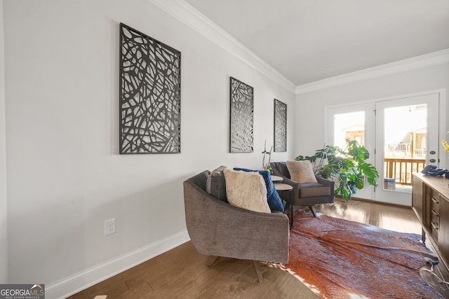 living area with ornamental molding, wood finished floors, and baseboards