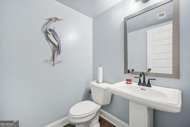 bathroom with visible vents, toilet, a sink, wood finished floors, and baseboards