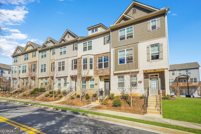 townhome / multi-family property with a residential view, board and batten siding, and brick siding