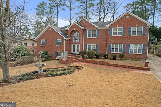 view of front of house featuring french doors, brick siding, fence, and a chimney