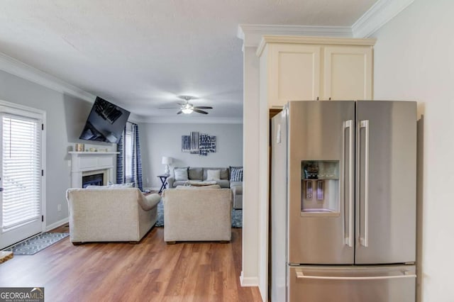 living area featuring ceiling fan, light wood-type flooring, a fireplace, and crown molding