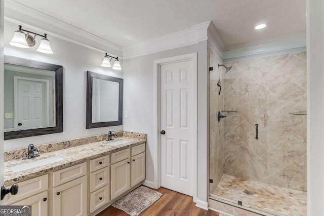 bathroom featuring a stall shower, crown molding, a sink, and wood finished floors