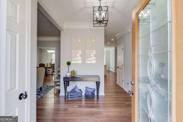 foyer entrance with a chandelier, ornamental molding, wood finished floors, and baseboards