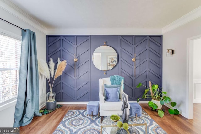 living area featuring ornamental molding, wood finished floors, and a decorative wall