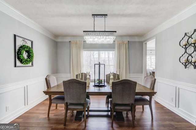 dining area featuring a chandelier, ornamental molding, dark wood finished floors, and a decorative wall