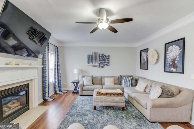 living room with ceiling fan, wood finished floors, a high end fireplace, baseboards, and ornamental molding