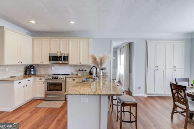 kitchen featuring appliances with stainless steel finishes, light wood-type flooring, a sink, and tasteful backsplash