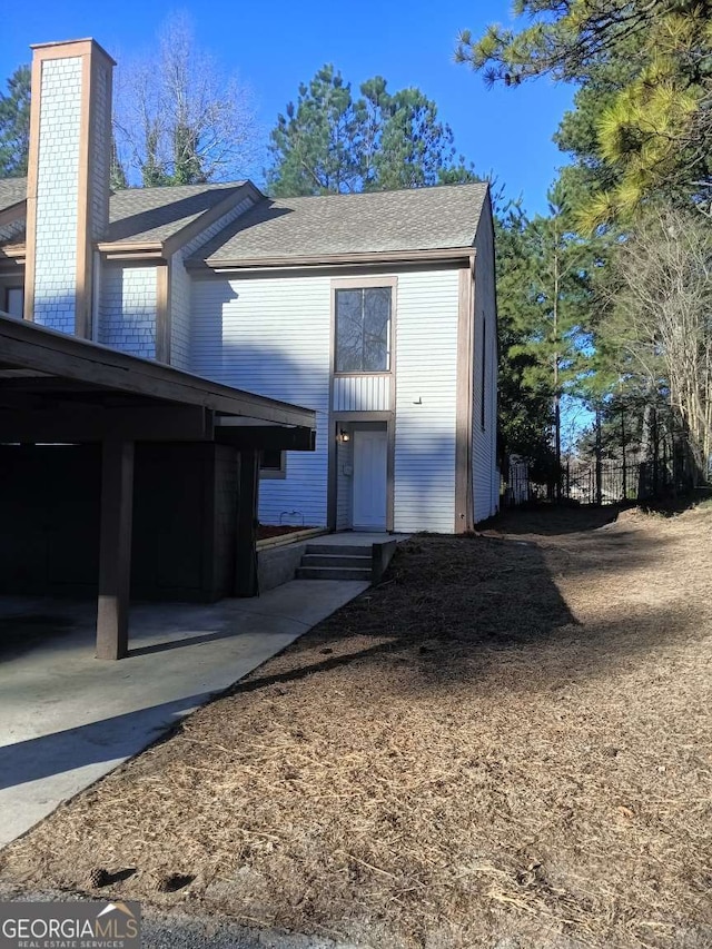 view of front of home with a shingled roof and a chimney