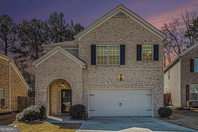 traditional-style house featuring a garage, concrete driveway, and brick siding