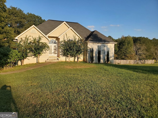 view of front of home featuring fence, a front lawn, and stucco siding