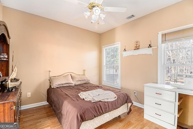 bedroom featuring light wood-type flooring, baseboards, visible vents, and a ceiling fan