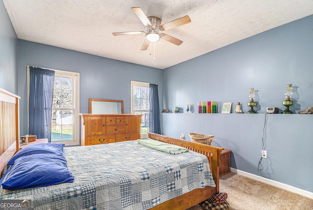 bedroom with a ceiling fan, a textured ceiling, baseboards, and carpet flooring