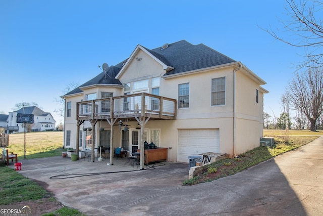 rear view of property featuring roof with shingles, a patio, an attached garage, and stucco siding