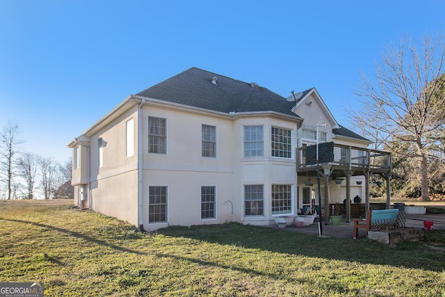 back of house featuring a yard, a patio, a shingled roof, and stucco siding