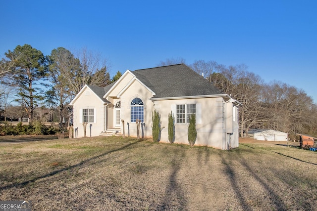 view of front of property featuring a shingled roof, a front yard, and stucco siding