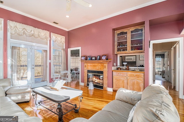 living area featuring light wood finished floors, plenty of natural light, crown molding, and french doors