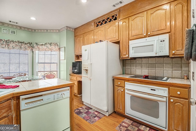 kitchen featuring tile countertops, white appliances, light wood-type flooring, and visible vents