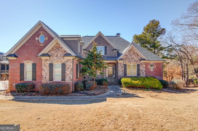 view of front facade featuring a front yard, stone siding, a chimney, and brick siding