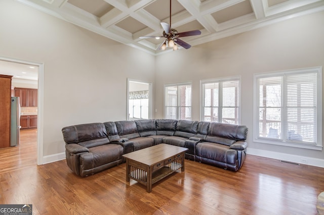 living room featuring a high ceiling, beam ceiling, coffered ceiling, and wood finished floors