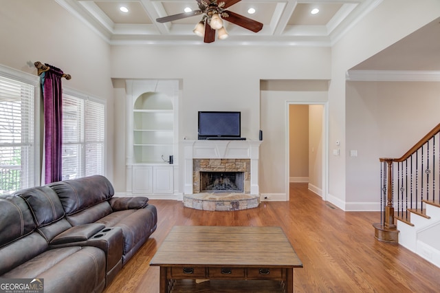 living room with built in shelves, a fireplace, stairway, a high ceiling, and light wood-type flooring