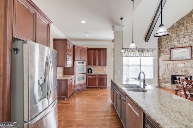 5016 Deer Creek Ct, Flowery Branch, GA 30542 - kitchen featuring a sink, a stone fireplace, stainless steel appliances, decorative light fixtures, and light wood-type flooring