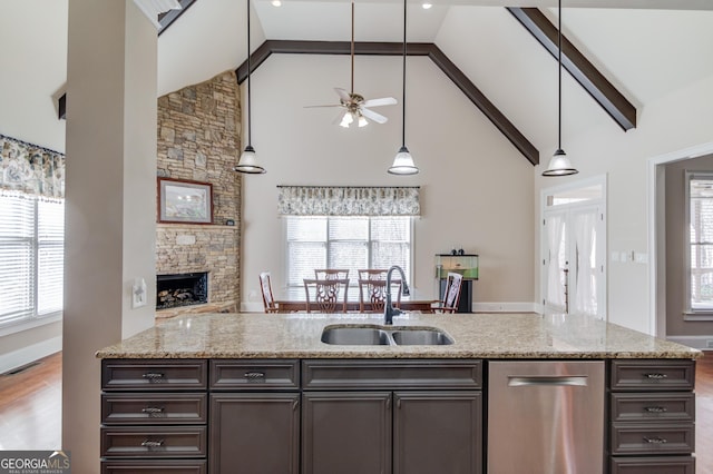 kitchen featuring light stone counters, a fireplace, a sink, visible vents, and dishwasher