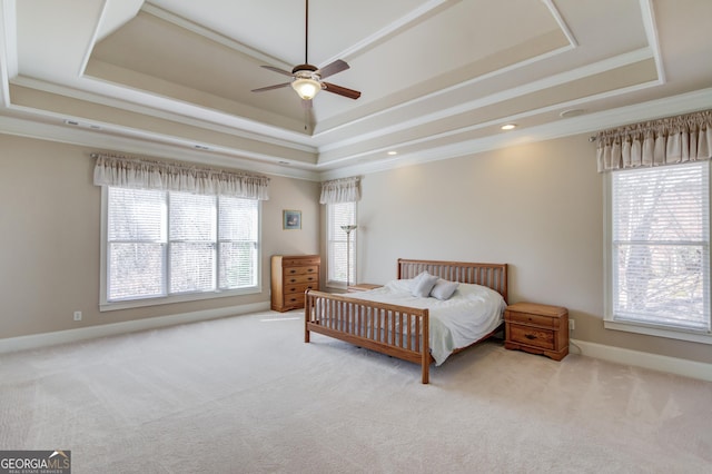 carpeted bedroom featuring baseboards, ceiling fan, a tray ceiling, and crown molding