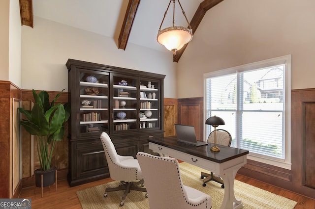 home office with lofted ceiling with beams, light wood-style flooring, and wainscoting