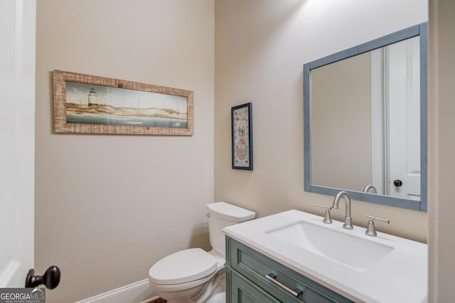 half bath with vanity, toilet, and baseboards