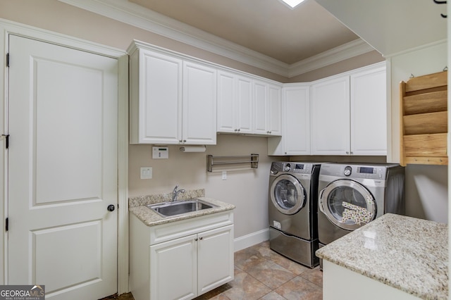 laundry area featuring cabinet space, ornamental molding, a sink, washer and dryer, and baseboards