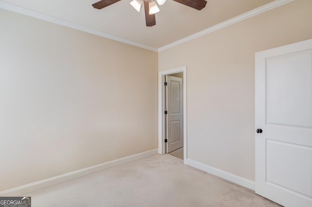 spare room featuring light carpet, a ceiling fan, baseboards, and crown molding