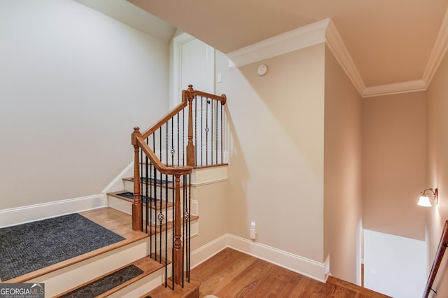 stairway with crown molding, baseboards, and wood finished floors