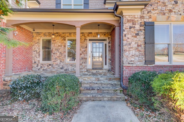 view of exterior entry featuring covered porch and brick siding