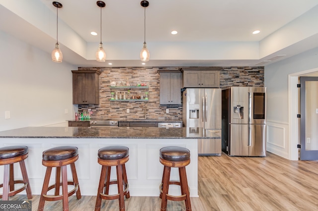 kitchen featuring stainless steel fridge, decorative backsplash, a breakfast bar, and a sink