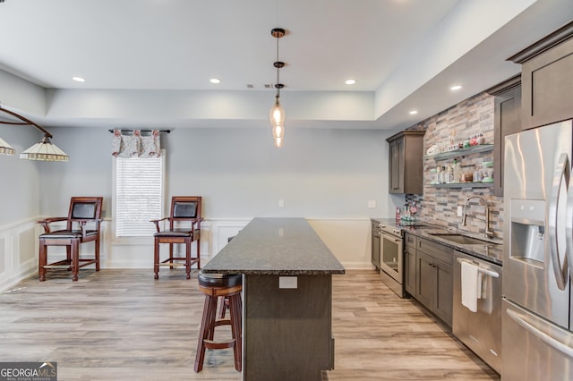 kitchen with a center island, stainless steel appliances, light wood-style floors, open shelves, and a sink