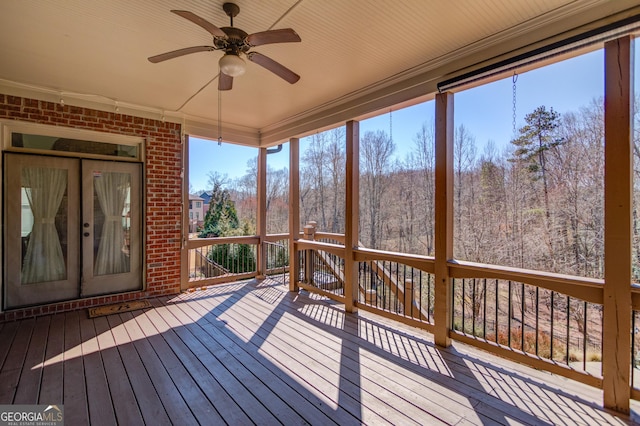 unfurnished sunroom with a forest view and ceiling fan