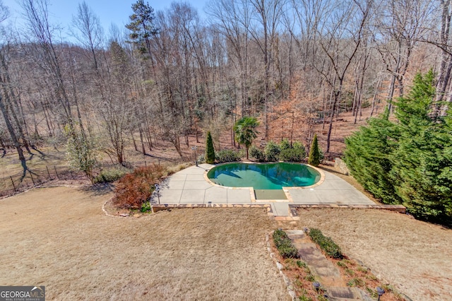 pool featuring a view of trees and a patio