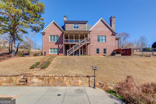 back of property featuring brick siding, fence, a chimney, and stairs