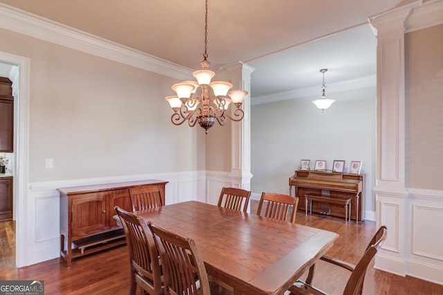 dining area featuring decorative columns, wainscoting, wood finished floors, an inviting chandelier, and crown molding