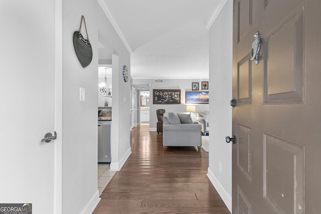 hall featuring ornamental molding, wood finished floors, visible vents, and baseboards