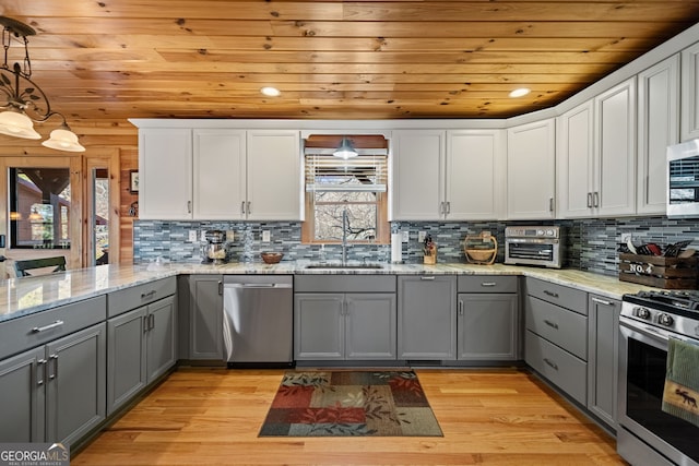 kitchen featuring stainless steel appliances, white cabinets, a sink, and gray cabinetry