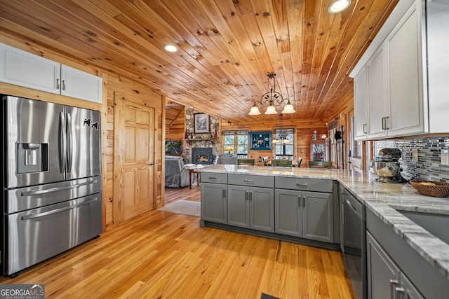 kitchen featuring open floor plan, a peninsula, stainless steel appliances, gray cabinetry, and pendant lighting